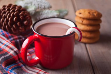 Ahşap masa üzerinde sıcak kakao, koni ve noel ağacı dalı kırmızı kupa ile Çerezler