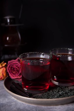 Kırmızı kokteyl ile iki bardak, karanlık arka plan üzerinde Cadılar Bayramı partisi için kurutulmuş gül