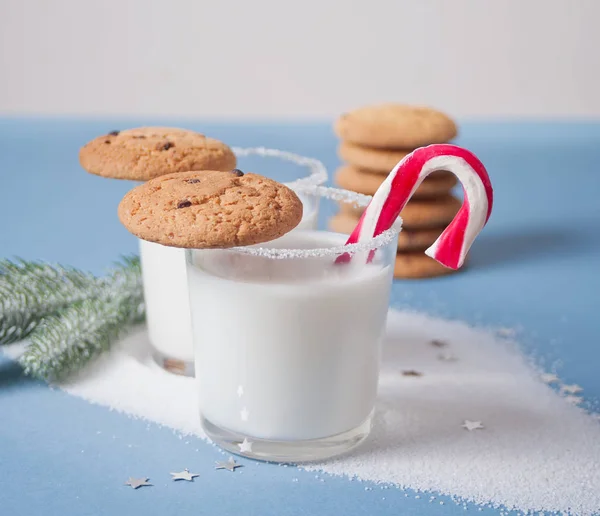 Copos de leite, biscoitos, cana-de-açúcar, ramo de árvore de natal no fundo azul — Fotografia de Stock