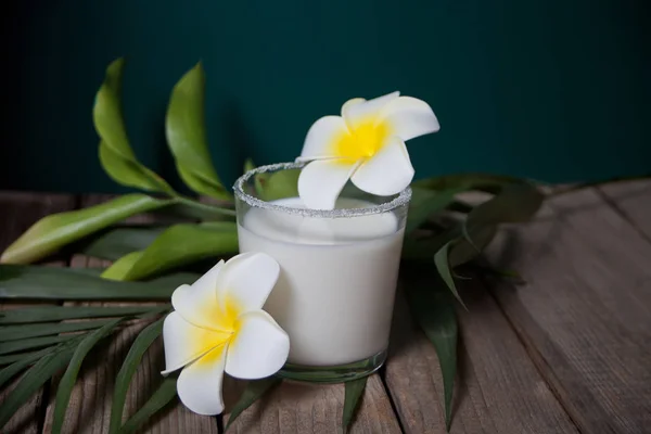Copo de leite de coco com flores plumeria e folha de palma no fundo de madeira — Fotografia de Stock