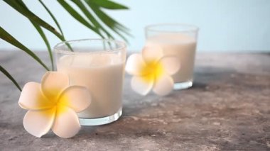 Çiçek plumeria ve sallanan palmiye yaprağı ile hindistan cevizi sütü Cam.