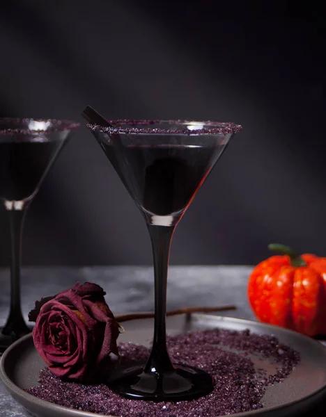 Два бокала с черным коктейлем, сушеные розы, тыква для Хэллоуина на тёмном фоне — стоковое фото