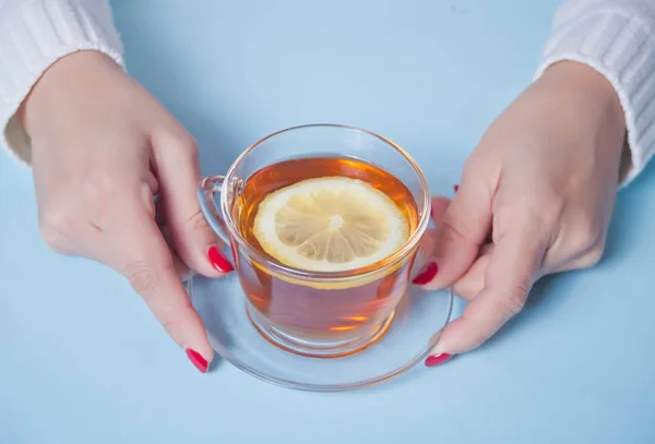 La mano de la mujer sosteniendo la taza de té con trozo de limón — Foto de Stock