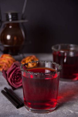 Kırmızı kokteyl ile iki bardak, karanlık arka plan üzerinde Cadılar Bayramı partisi için kurutulmuş gül