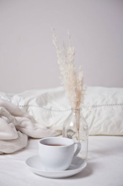 Bir fincan çay, süt ve bir buket beyaz çiçek yakın.