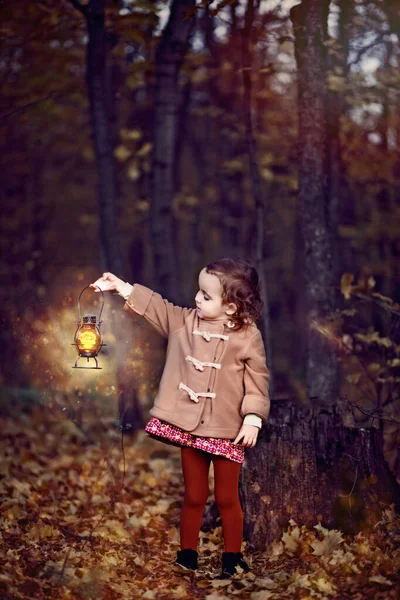 Portrait de conte de fées de petite fille en manteau marron avec foudre magique dans la forêt d'automne nocturne — Photo