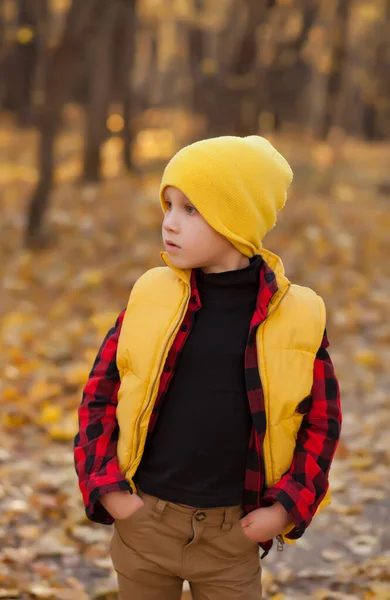 Chlapec na žluté čepici stojící venku. Podzimní čas. Šťastné dítě si hraje na podzimním přírodním pozadí. Dětská podzimní móda. Šťastné dětství — Stock fotografie