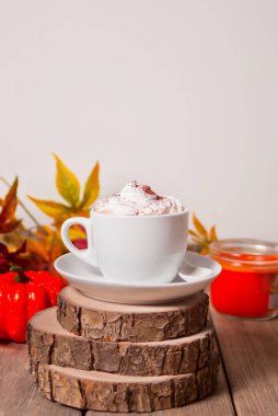 Arka planda sonbahar yaprakları ve kabaklar ile köpük ile sıcak kremsi kakao Fincan