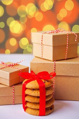 Farklı boyutlarda Noel hediyesi kutuları, bulanık bokeh arka planında mevcut ev yapımı kurabiyeler.
