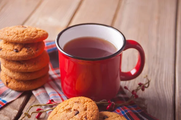 Galletas con taza roja de té caliente o café en la mesa de madera — Foto de Stock