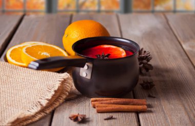Eski metal tencere lezzetli sıcak şarap baharatlı ve ahşap masada portakal meyveli.