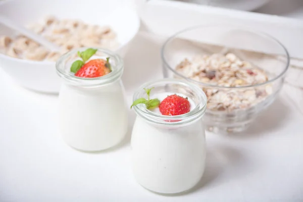 Duas porções de iogurte caseiro natural em um frasco de vidro com morango fresco e muesli nas proximidades — Fotografia de Stock