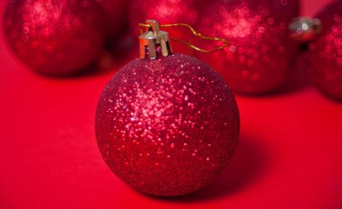 Kırmızı Noel topları kırmızı arka planda parlıyor
