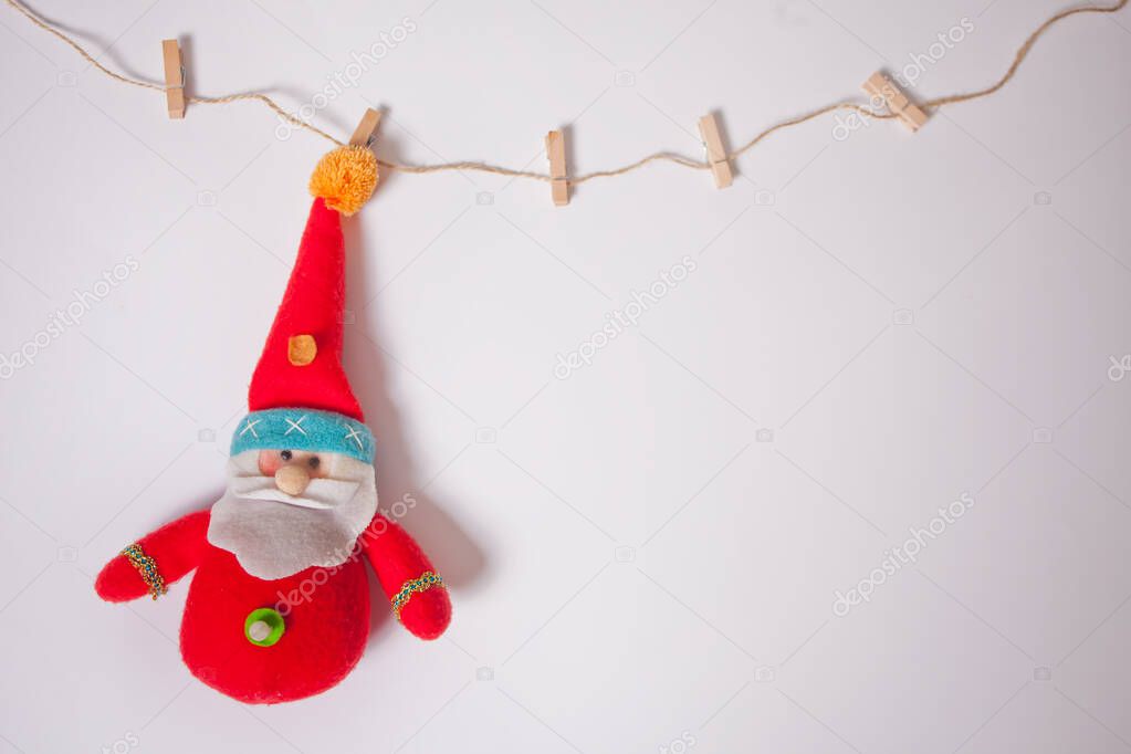 Miniature Christmas funny toy Santa hanging on the clothes pin on a white background