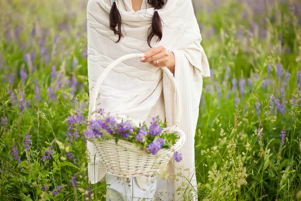女性ピッキングライラック花でウィカーバスケット上の牧草地. — ストック写真
