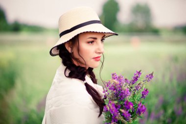 Çayırda leylak çiçekleri tutan kadın.