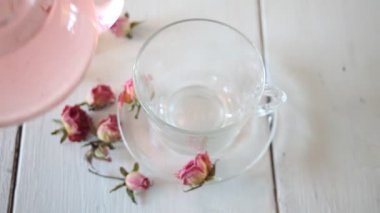 Kadın eli fincana gül çayı dolduruyor. Sağlıklı bitkisel detoks çayı.