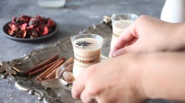Kadın eli, masanın üzerinde süt ve baharat olan bir çay al.