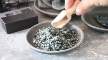 Kadın eli kaşık kömür kozmetik ve cilt tuzu ile karıştırıyor. Spa ve banyo konsepti