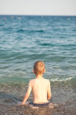 Oğlan güneşli bir yaz gününde deniz veya okyanus dalgalarında eğleniyor. Okyanus kıyısı ve sahil. Aktif yaşam tarzı ve eğlence konsepti.