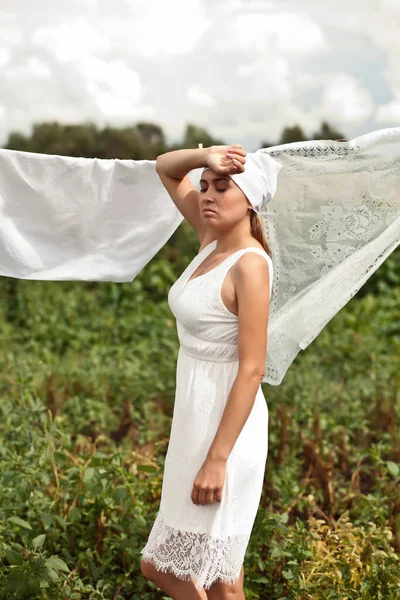 Young woman in a white dress hanging up laundry outdoor — Stock Photo, Image