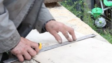 Yaşlı marangoz tahtaya çizgi çekmek için düz bir çizgi kullanıyor.