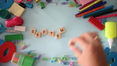 Mavi arka planda okul malzemeleri var. Eylül 'de kadın eli ile ahşap kelimeler.