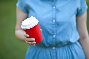 Elinde tek kullanımlık kahve tutan bir kadın.