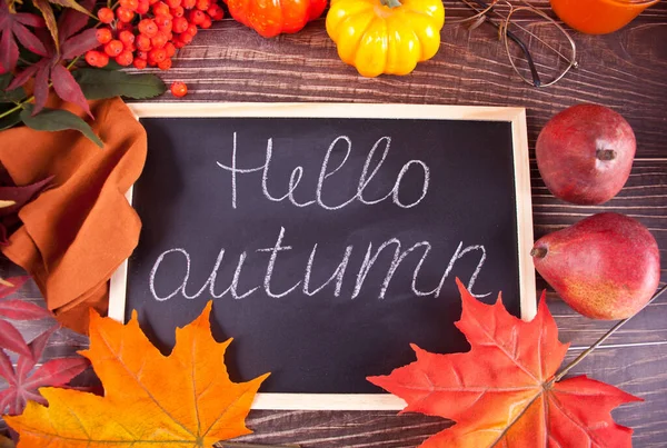 Доска с текстом Hello Autumn. Состав с тыквой, осенними листьями и красными грушами. Уютная осенняя концепция. — стоковое фото