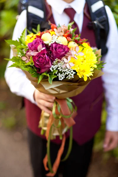 Little boy with a backpack and flowers in a hand go to school. — Stock Photo, Image