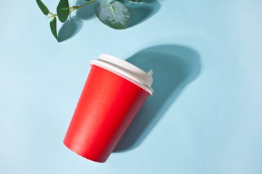 Kırmızı kahve fincanı ve mavi arka planda ev bitkisi. Model yap. Üst görünüm.