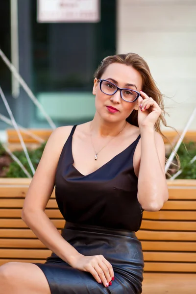 ベンチに座っている眼鏡のきれいな女性 ロイヤリティフリーのストック写真