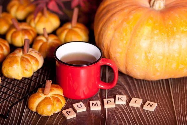 Pumpkin buns on the baking rack and cup of tea. Autumn concept. Warm and cozy.