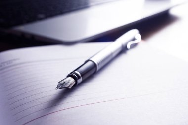 Dizüstü bilgisayar, ajanda, kalem, telefon ile bir resepsiyon çalışma alanı gösterilen yüksek çözünürlüklü görüntü.