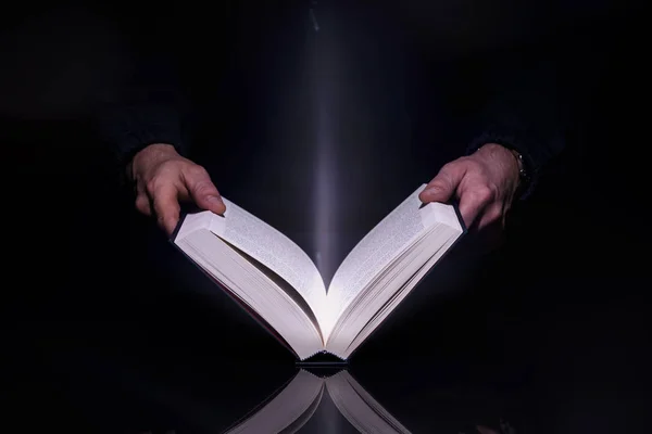 İçinden gelen parlayan ışıkla kitap okuyan kişi. Yüksek resolutin görüntü.