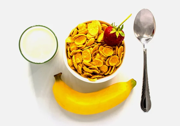 Mısır gevreği, süt, muz ve beyaz arka planda çilek.