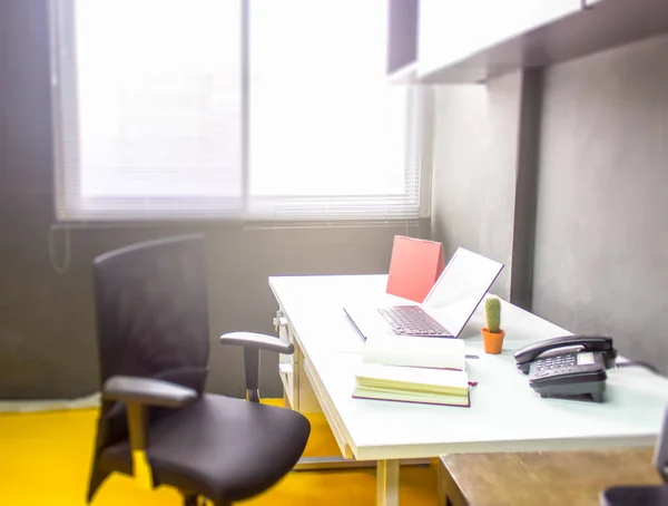 Dizüstü bilgisayarı olan işyeri ofis pencerelerinde çalışma masası