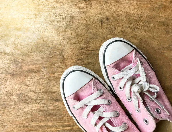Ahşap arka planda pembe tuval ayakkabılar, kadın ayakkabıları.