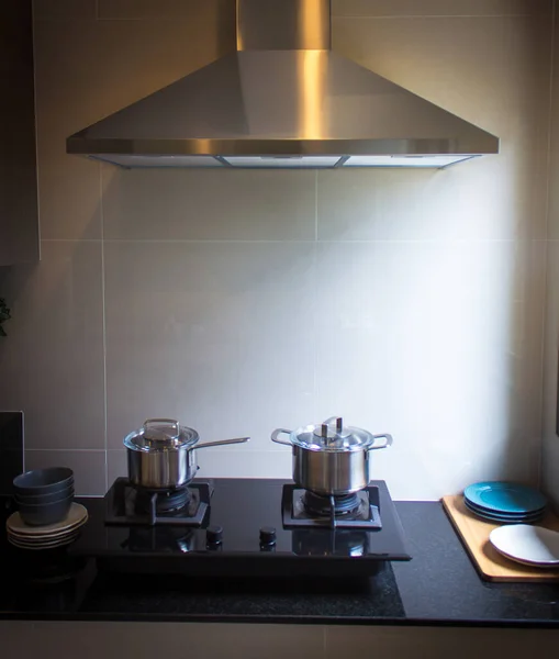 Mutfaktaki siyah gaz sobasında paslanmaz çelik tencere. 