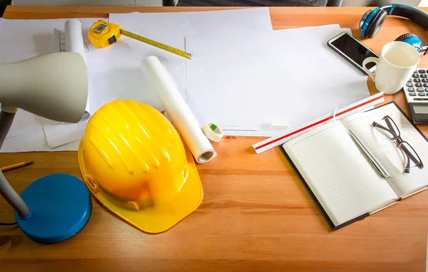 Çalışma masası ve mimarın çalışma ekipmanları ofiste, sarı güvenlik kaskı.