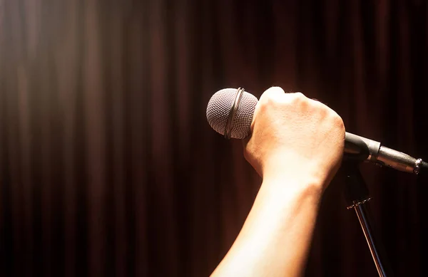 Erkeklerin eli mikrofon tutuyor. Kırmızı perdeler arka planda fotokopi alanı var.