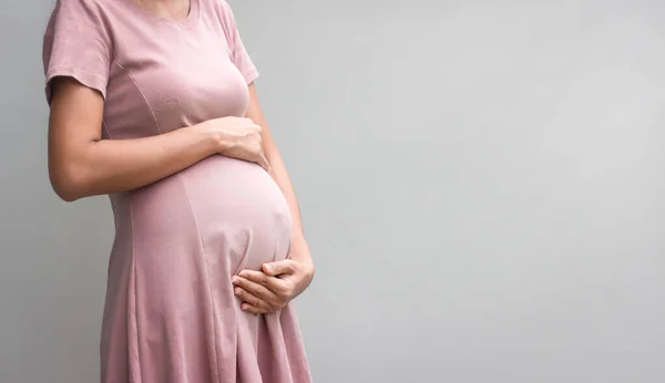 Hamile kadın beyaz arka planda el ele tutuşuyor. konsept. Yakın plan, kopyalama alanı.