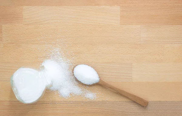 Tahta arka planda tahta kaşıkta beyaz şeker ve şeker kavanozu fotokopi alanı ile