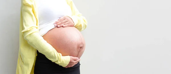 妊娠中の女性は白い背景に腹を手に持っています コピースペース ロイヤリティフリーのストック写真