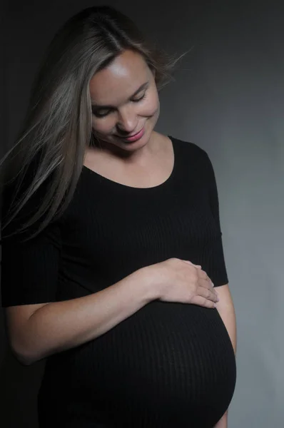 Portrait studio d'une femme enceinte sur fond sombre — Photo