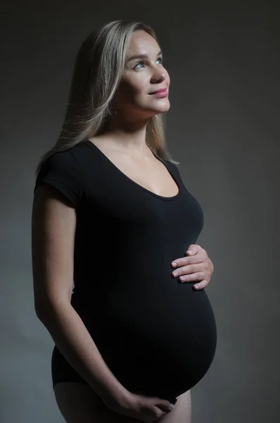 Studio-portrett av en gravid kvinne med mørk bakgrunn – stockfoto