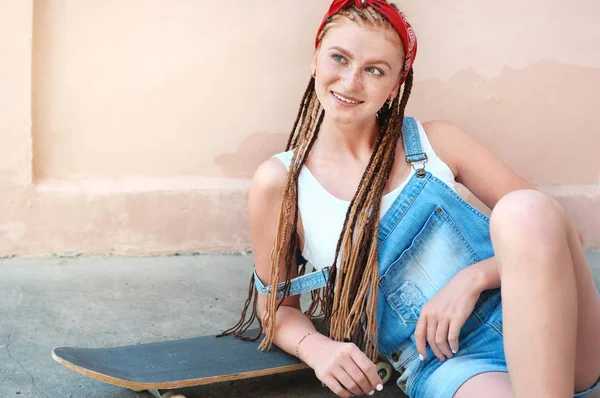 Capelli rossi ragazza adolescente con lentiggini in stile casual con skateboard in giornata estiva per strada — Foto Stock