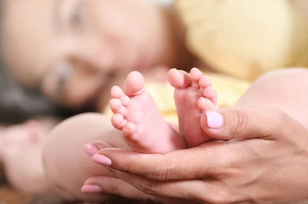 Dispara de cerca de las manos de la madre sosteniendo los pies del pequeño bebé. Pequeño bebé cuidador de padres —  Fotos de Stock