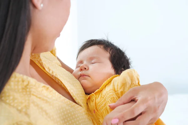 Mujer joven y bonita sosteniendo a un bebé recién nacido en sus brazos. Concepto de familia feliz . —  Fotos de Stock