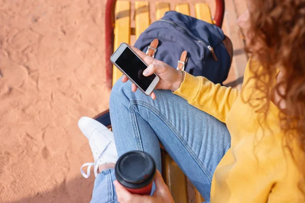 Close-up tiro do telefone na mão menina do estudante ter uma pausa com café fora no parque de outono — Fotografia de Stock